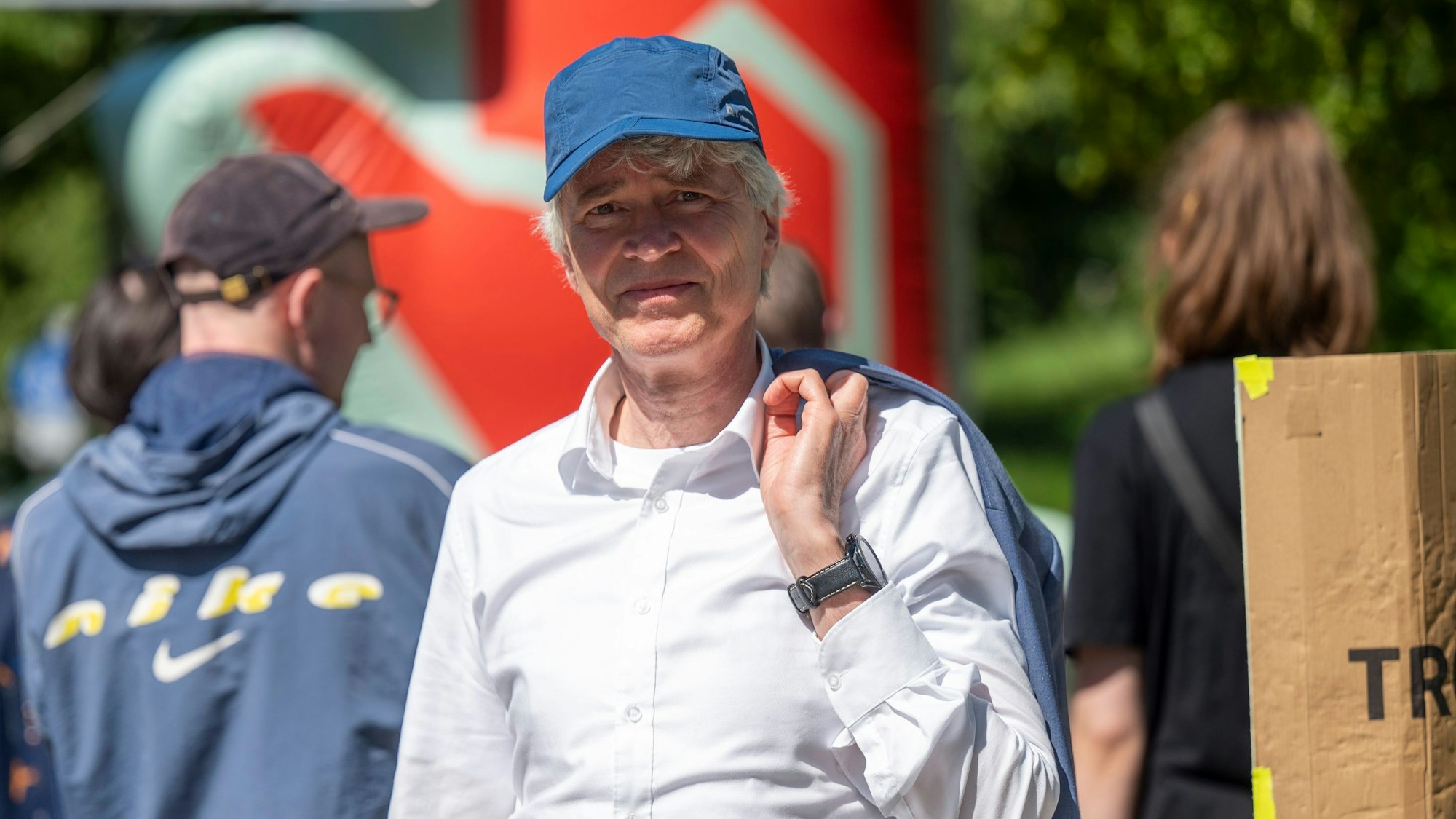 Mann mittleren Alters mit weißem Hemd und blauer kappe, der in die Kamera schaut