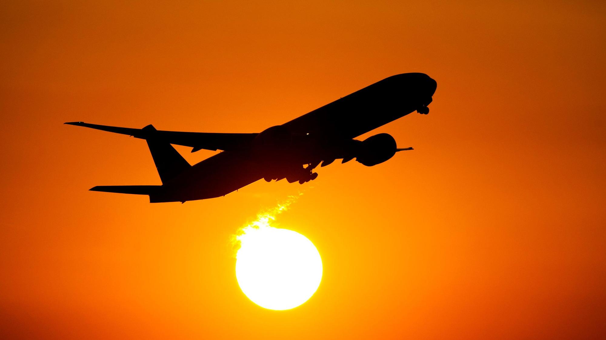 Ein Flugzeug startet in den Sonnenuntergang. (Symbolbild)