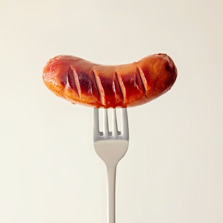 Eine kleine Bratwurst ist auf eine Gabel gespießt.