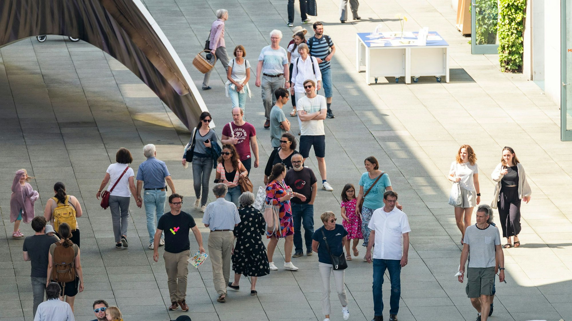 Viele Menschen gehen über einen gepflasterten Platz.