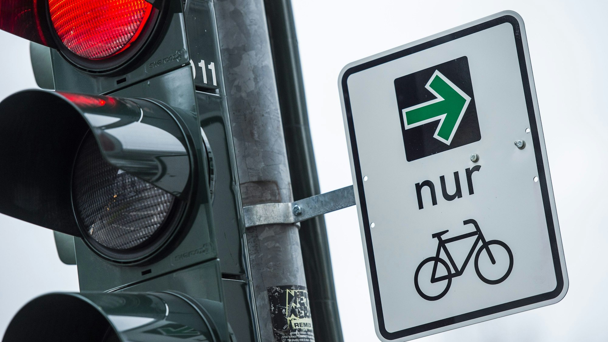 An einer Ampel einer Kreuzung hängt ein grüner Pfeil, der es Fahrradfahrern erlaubt rechts abzubiegen, wenn die Ampel rot ist.