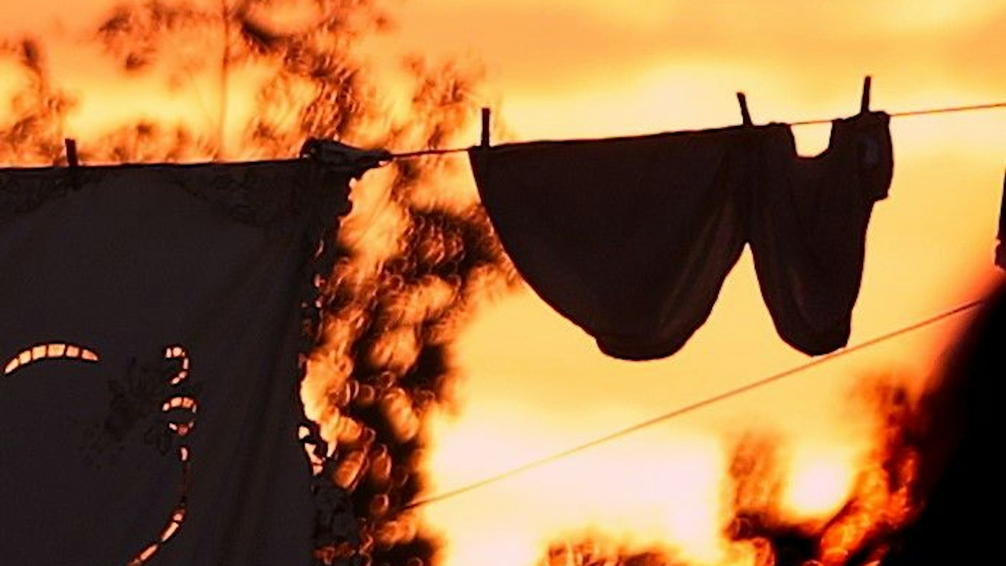 Kleidungsstücke hängen bei Sonnenuntergang an einer Wäscheleine (Symbolfoto).
