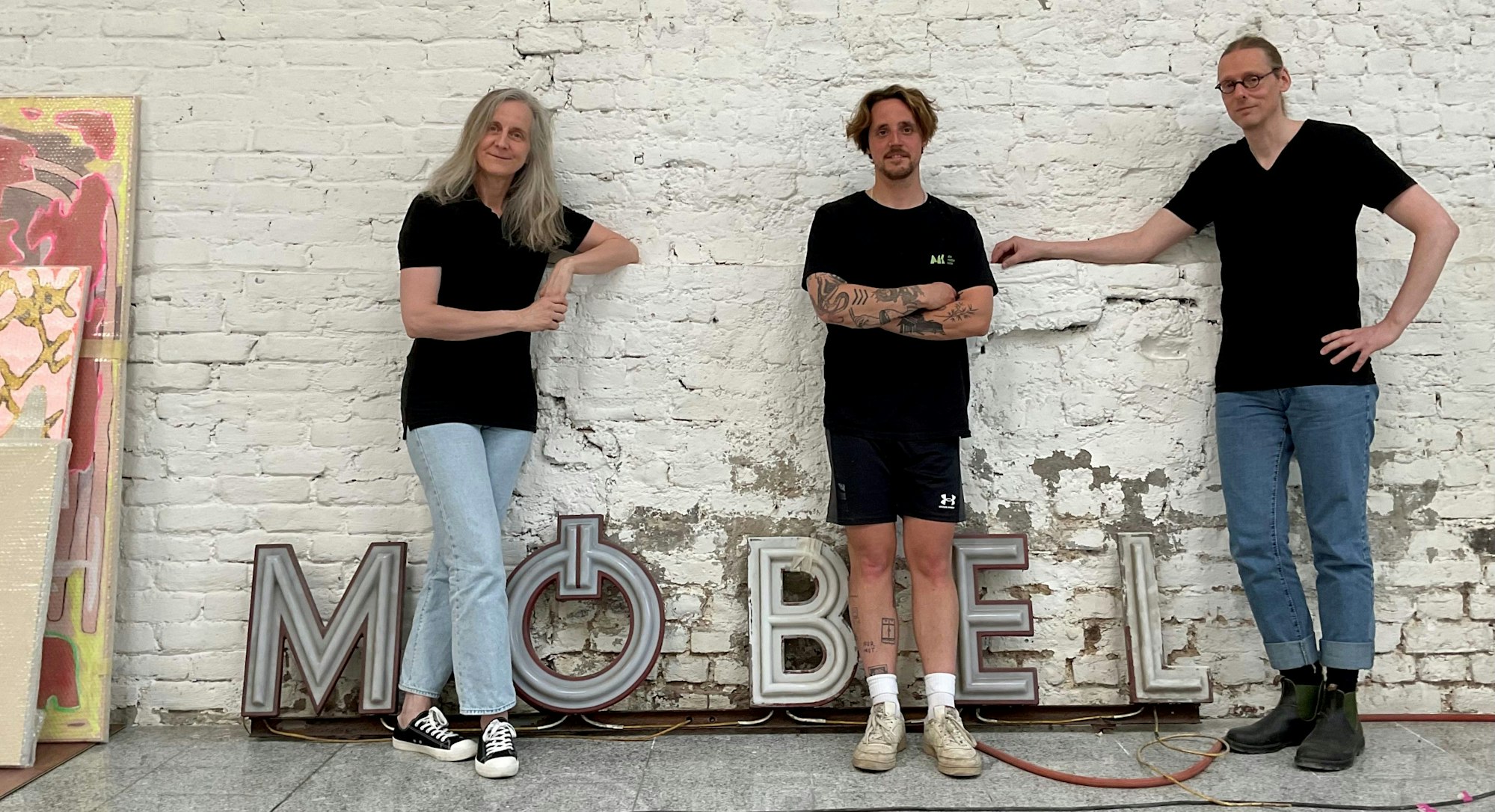 Drei Personen vor einer alten Möbel-Leuchtreklame