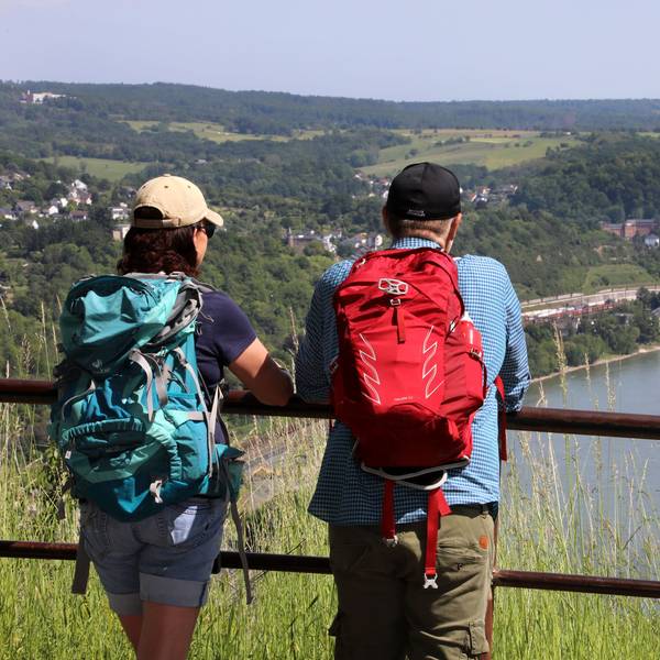 Zwei Wanderer schauen von einer Anhöhe auf den Rhein
