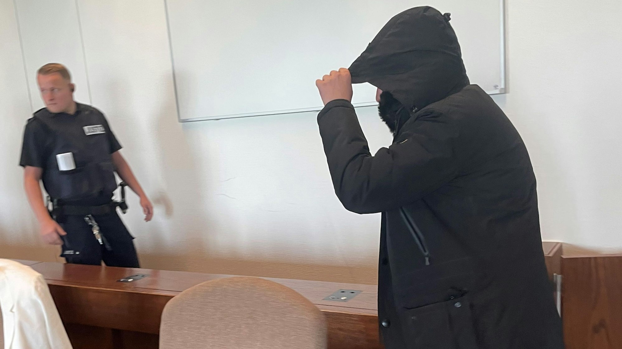 Der Angeklagte wird von einem Wachtmeister in den Saal im Landgericht Köln gebracht.