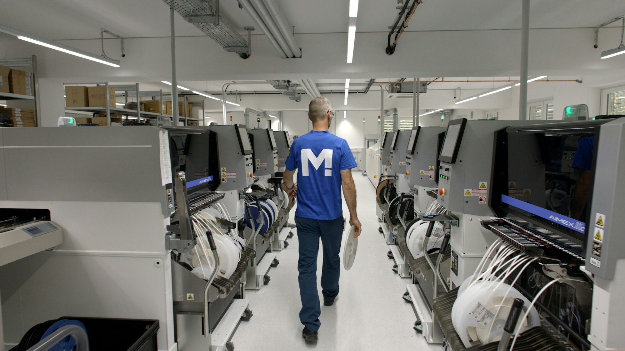 Es sind mehrere Computer zu sehen. Ein Mann geht durch den Gang.