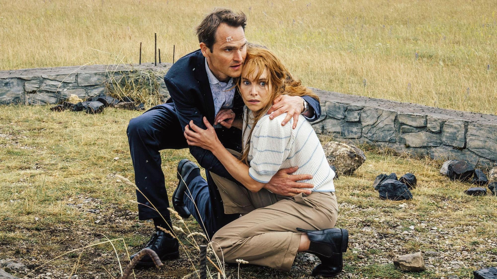 Felix Voss (Fabian Hinrichs) und Eva Hentschel (Sina Martens) gehen in Deckung. Hinter ihnen sieht man die steinernen Überbleinsel einer Hütte.
