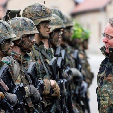 Es ist Boris Pistorius in Kleidung der Bundeswehr zu sehen. Er ist umgeben von mehreren Soldaten.