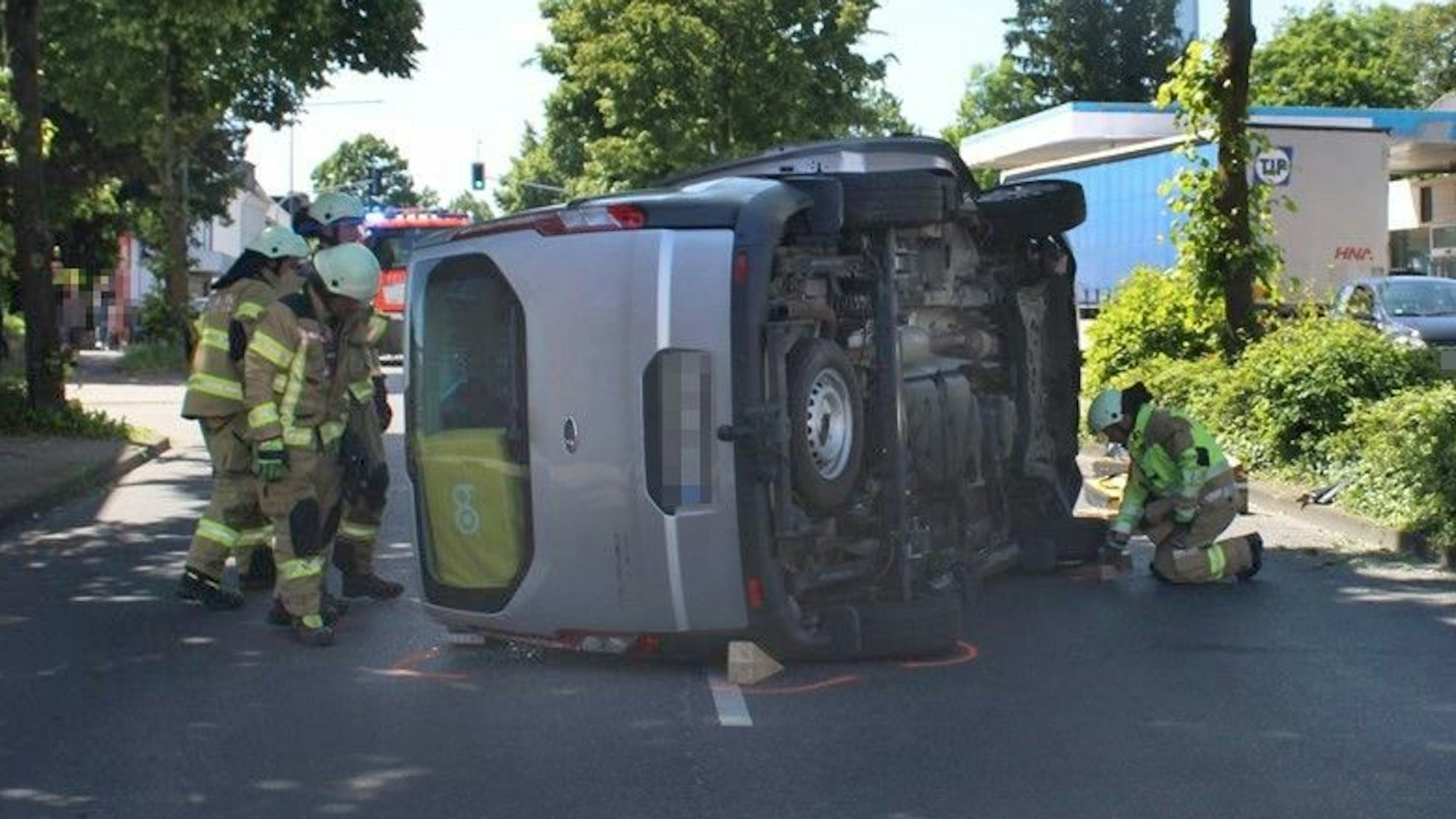 Auf der Straße liegt ein umgekippter Wagen. Feuerwehrleute kümmern sich um den Unfall.