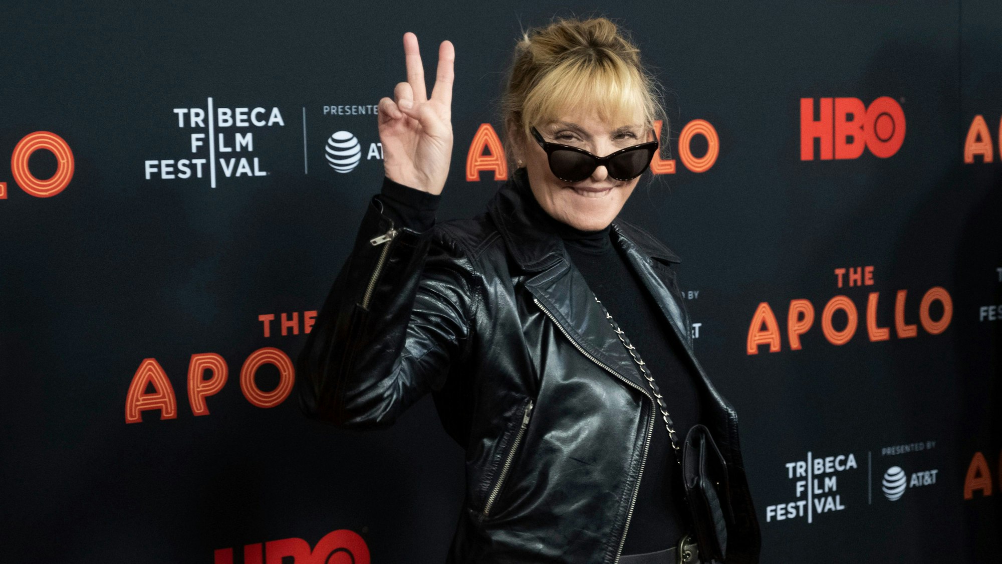 Kim Cattrall auf dem roten Teppich. Sie macht das „Peace“-Zeichen mit einer Hand.