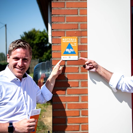 Der Kreis Euskirchen hat das Prinzip der Notfallmeldestellen vorgestellt. Zu erkennen sind die Anlaufstellen an den Plaketten. Landrat Markus Ramers und Zülpichs Bürgermeister Ulf Hürtgen am Feuerwehrgerätehaus in Juntersdorf.