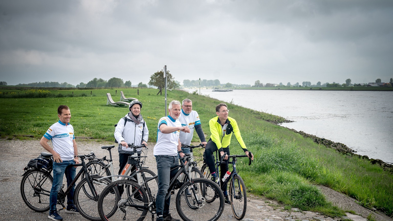 Am Rhein: Frank Sundermann (Stadt Kalkar/m.) erklärt den vier Testfahrern (v.l.) Gregor Espenkott (WestLotto), Bastian Bender (WDR 4), Axel Weber (WestLotto) und Stefan Neubauer (NRW-Stiftung) die Landschaft.