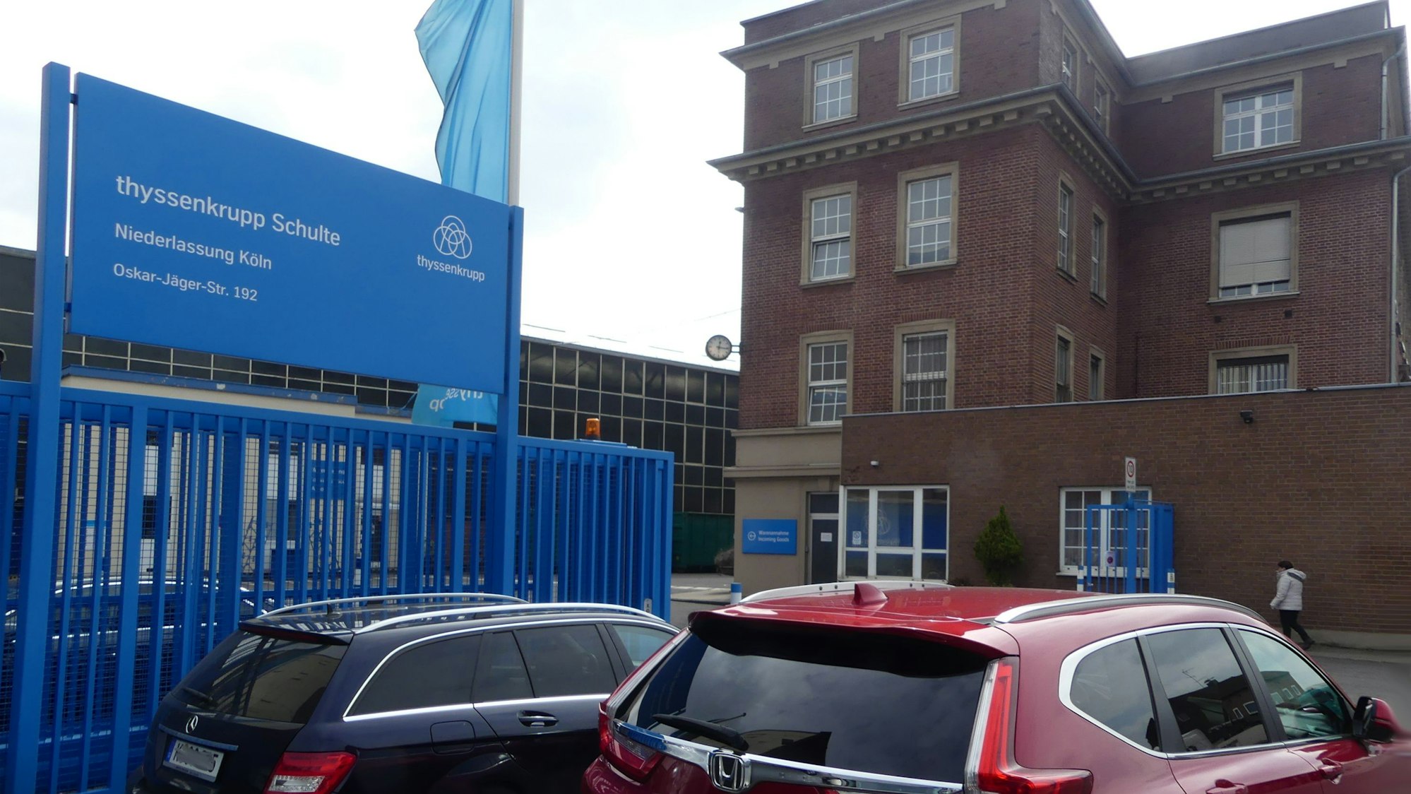 Vor dem Eingang zu einem Werksgelände parken zwei Autos. Auf einem Schild ist der Firmenname Thyssenkrupp Schulte zu lesen.