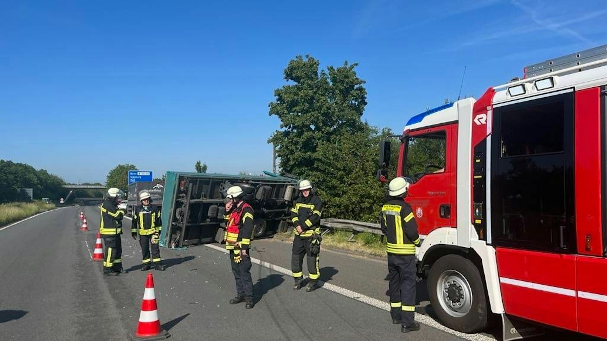 Der Lkw liegt auf der Seite. Einsatzkräfte der Feuerwehr und ein Feuerwehrauto sind zu sehen.