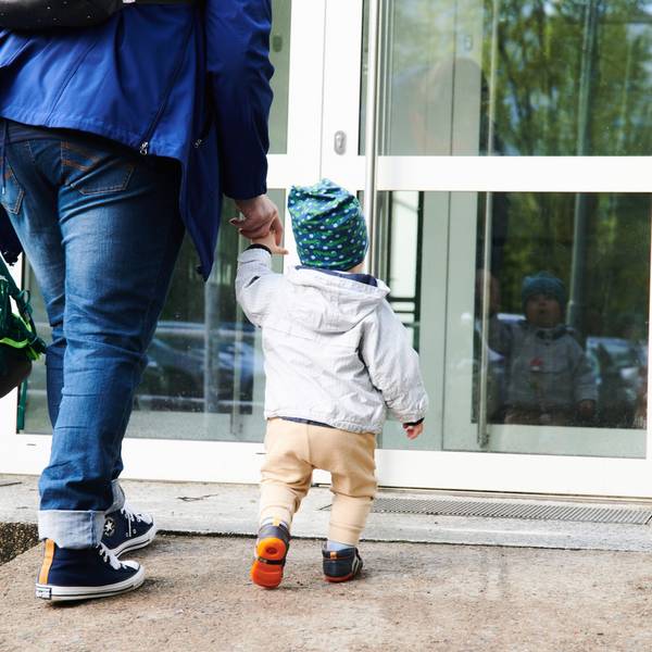 Ein Kind und seine Mutter gehen zum Eingang einer Kita.