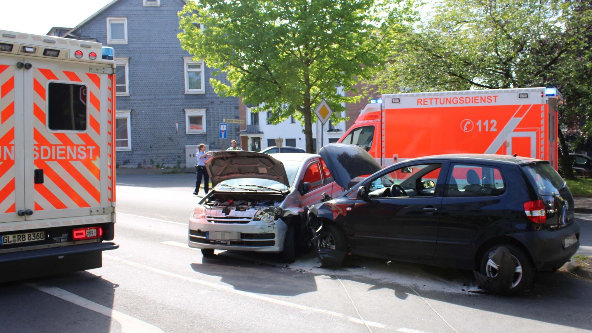 Zwei kollidierte Autos, umrahmt von Rettungswagen, in der Burscheider Innenstadt.