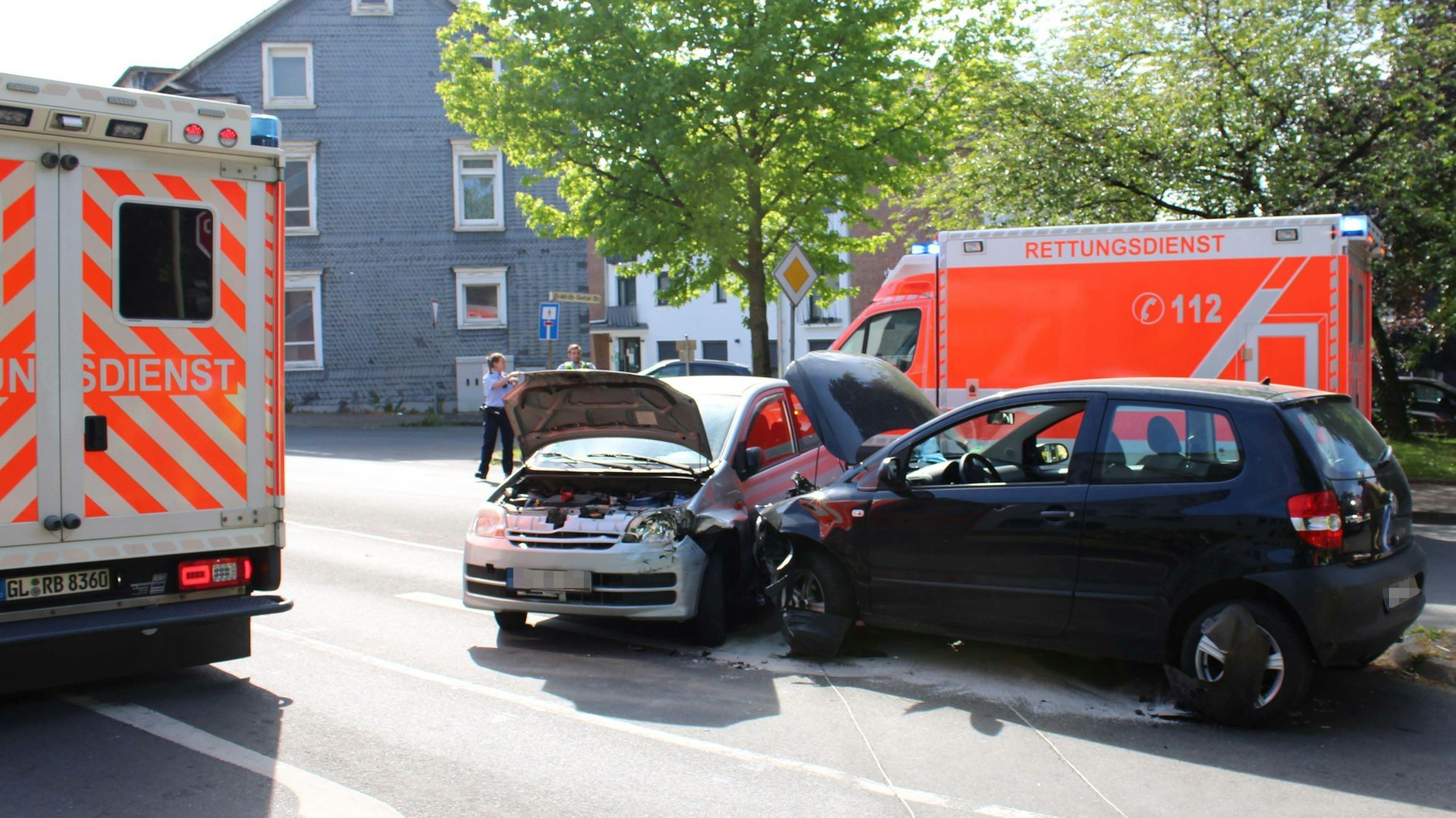Zwei kollidierte Autos, umrahmt von Rettungswagen, in der Burscheider Innenstadt.