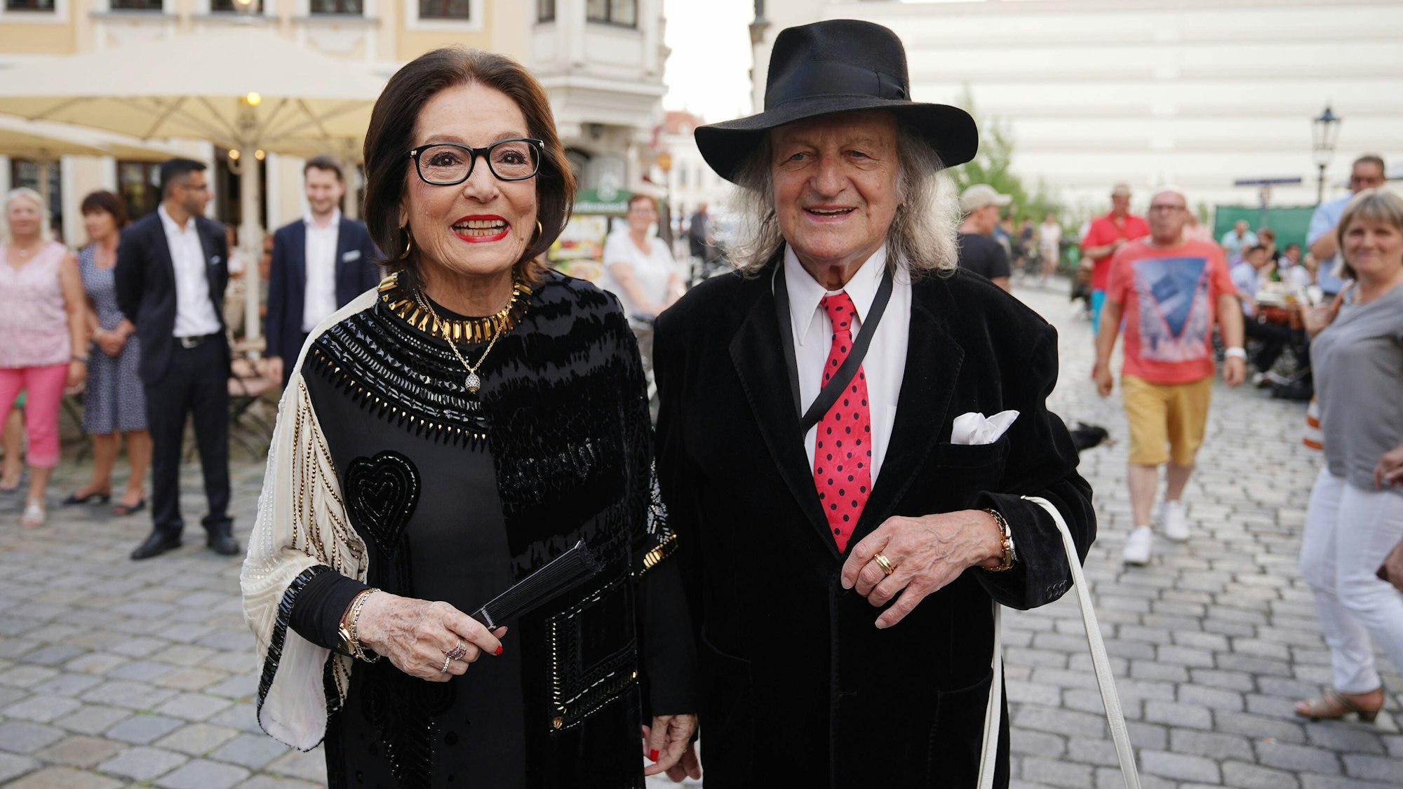 Nana Mouskouri und ihr Ehemann André Chapelle auf der Straße. Beide lächeln.