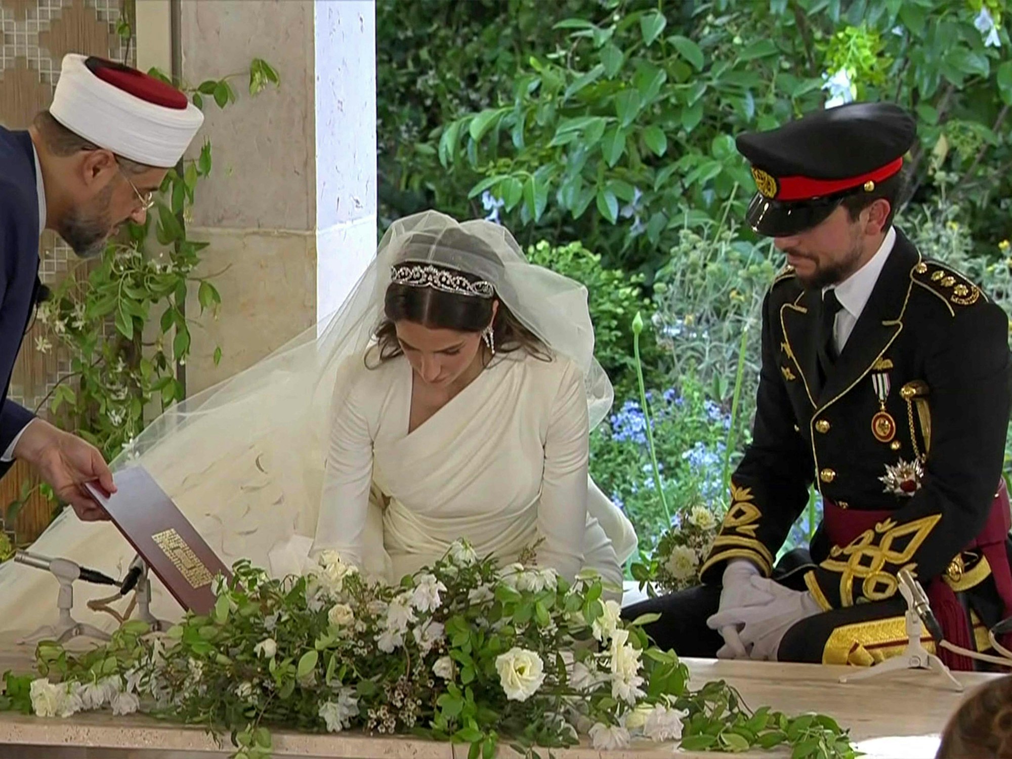 Der Screenshot eines vom jordanischen Königspalast veröffentlichten Fotos zeigt Kronprinz Hussein (r) und seine Frau Saudi Rajwa al-Seif bei der Unterzeichnung von Dokumenten während ihrer Hochzeitszeremonie