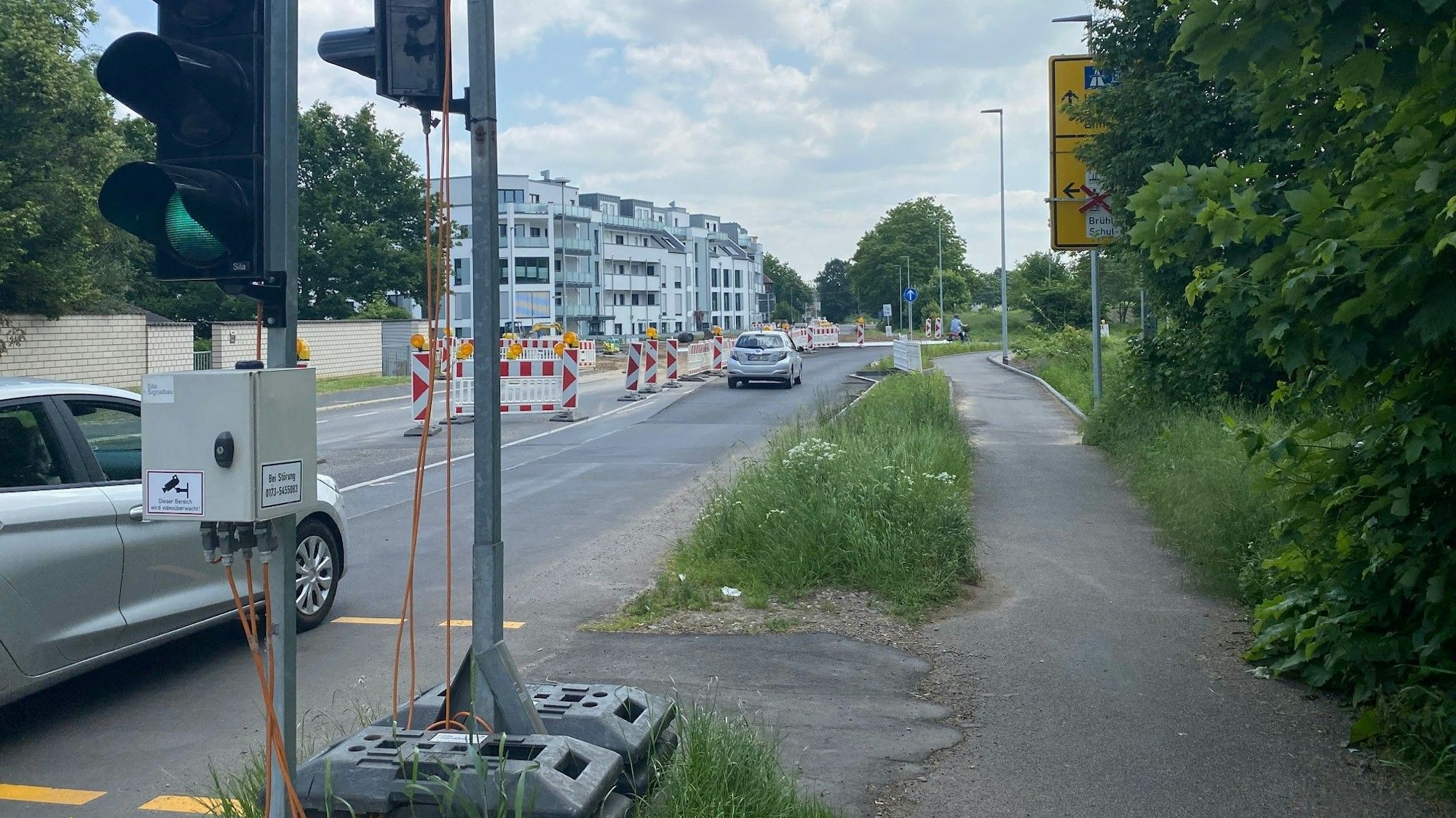 Das Foto zeigt eine Baustellenampel und eine verengte Fahrspur: Die Arbeiten zur Errichtung des neuen Kreisverkehrs an Alte-Bonnstraße und Otto-Wels-Straße werden länger dauern, als ursprünglich geplant.