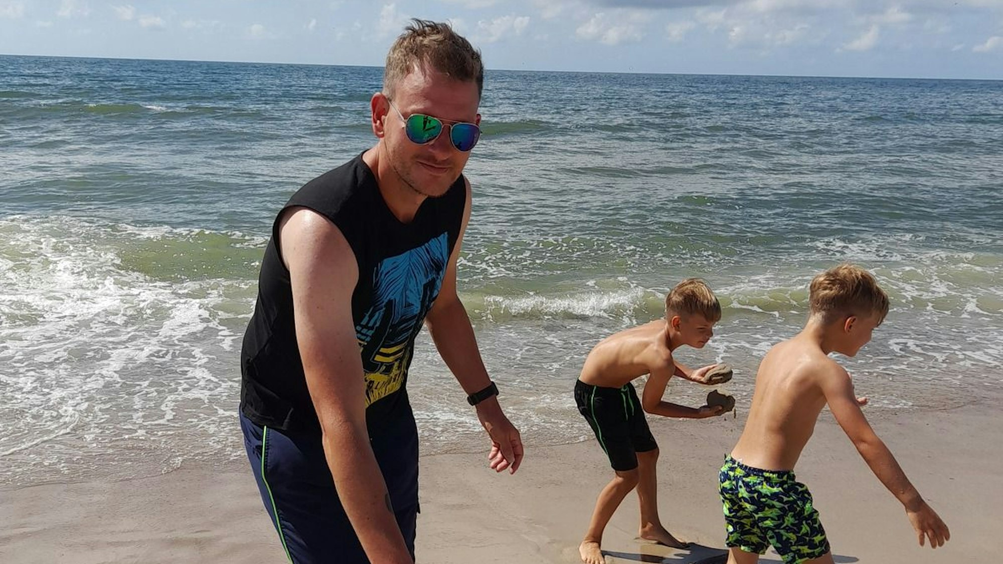 Ein Mann spielt am Strand mit seinen Kindern.