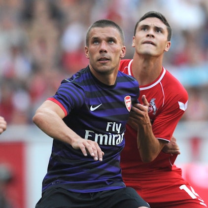 Lukas Podolski (M.) vom FC Arsenal wehrt sich im August 2012 im Testspiel gegen Jonas Hector (r.) vom 1. FC Köln, Lukas Kübler (l.) schaut zu.