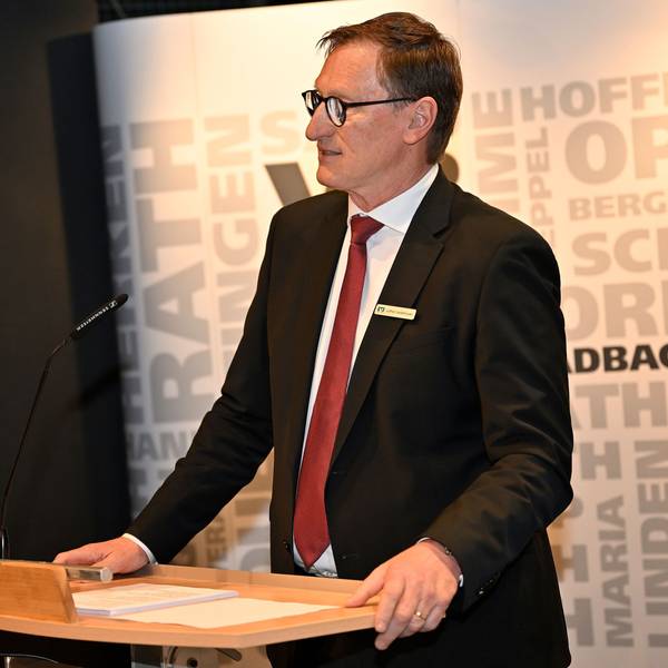 Ein Mann in Anzug und Krawatte steht an einem Rednerpult.