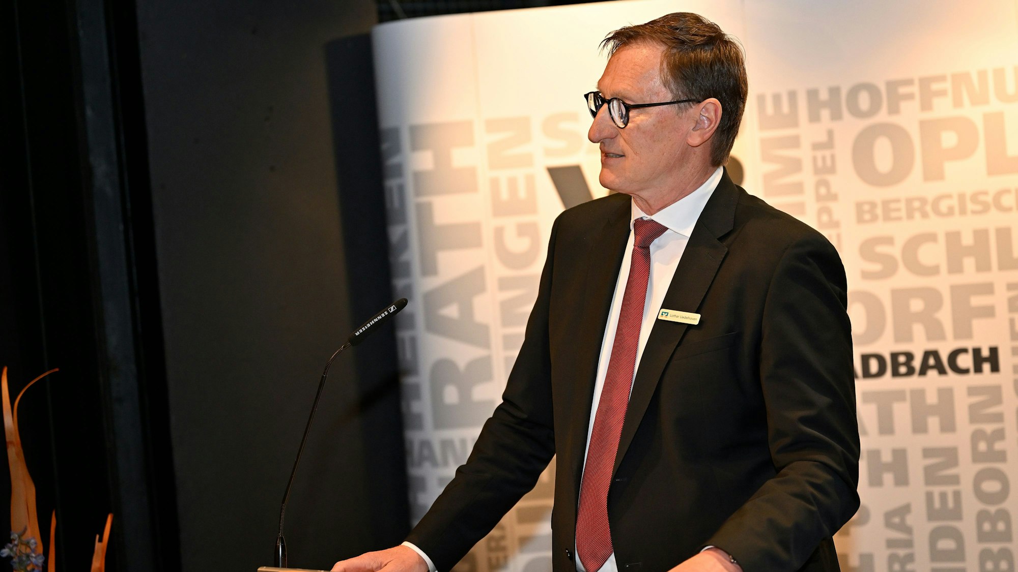 Ein Mann in Anzug und Krawatte steht an einem Rednerpult.