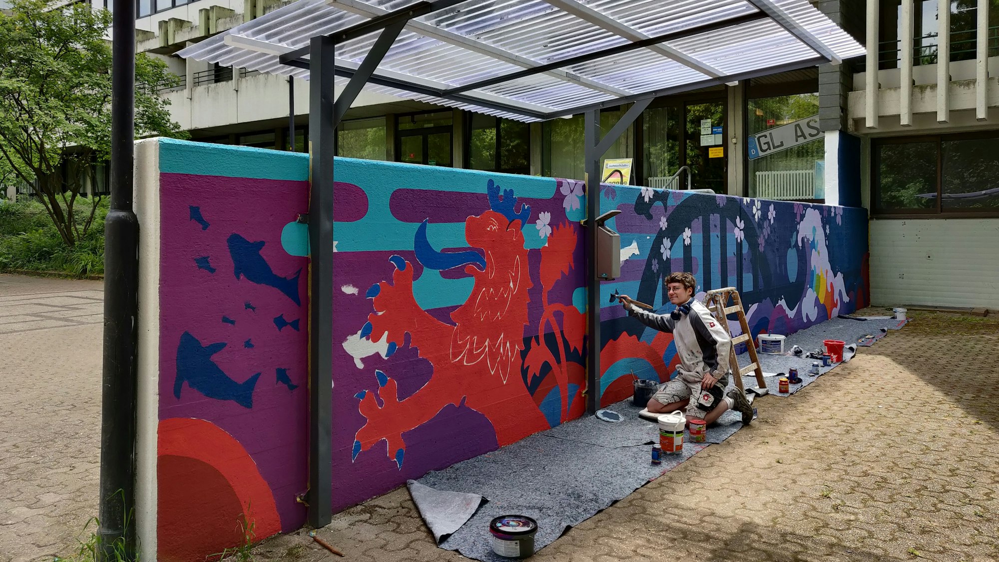 Logan Kleefisch bei den letzten Farbtupfern für sein Wandgemälde auf der Mauer hinterm Rathaus.