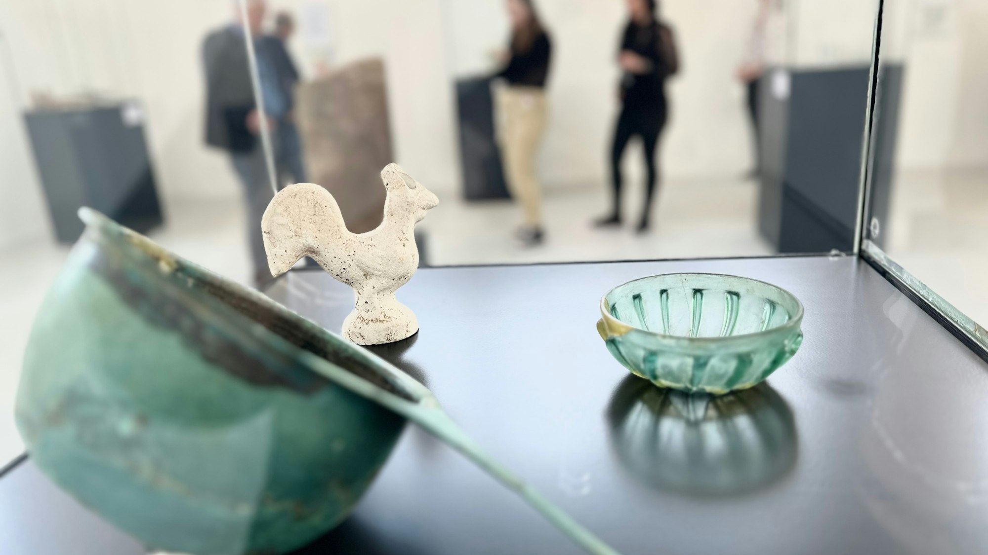 Glas- und Steinobjekte stehen in einer Vitrine.