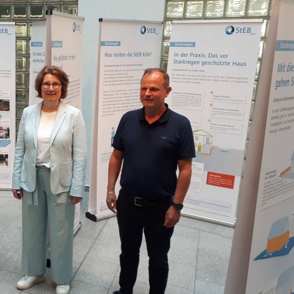 Zwei Frauen und ein Mann stehen zwischen Ausstellungstafeln im Foyer des Rathauses von Nippes.
