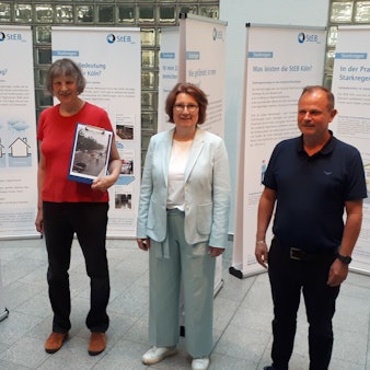 Zwei Frauen und ein Mann stehen zwischen Ausstellungstafeln im Foyer des Rathauses von Nippes.