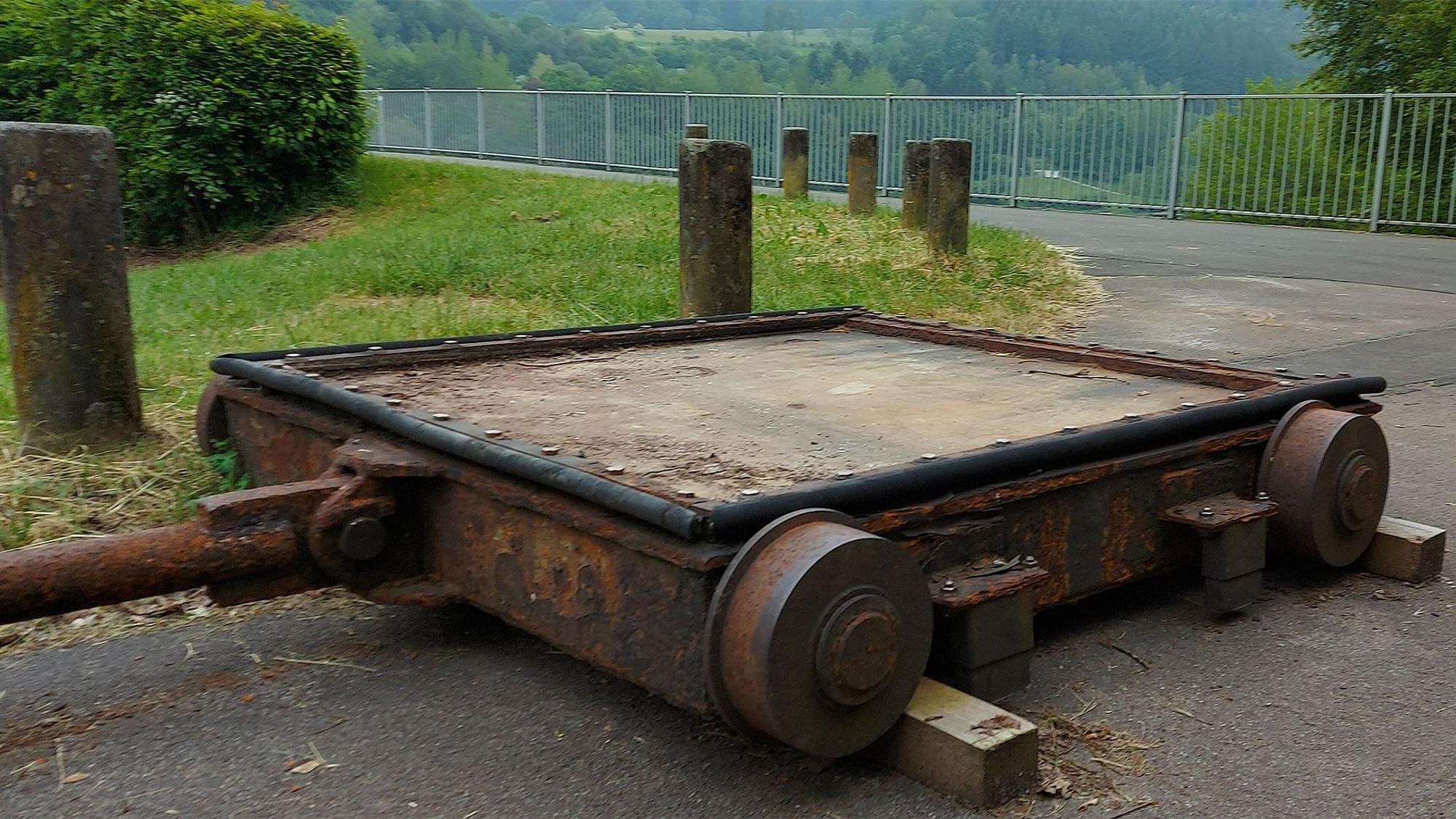 Das Bild zeigt ein Betriebsschütz, das aus der Talsperrenmauer ausgebaut wurde und nun an einem asphaltierten Weg liegt.