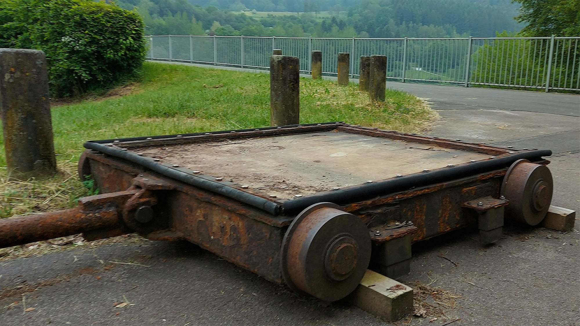Das Bild zeigt ein Betriebsschütz, das aus der Talsperrenmauer ausgebaut wurde und nun an einem asphaltierten Weg liegt.