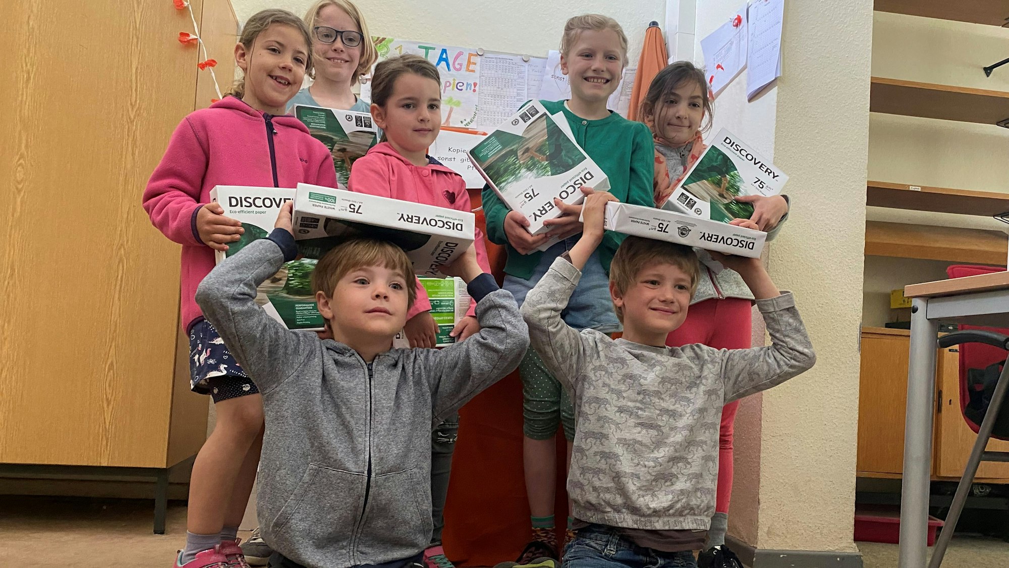 Grundschulkinder halten Druckpapier.