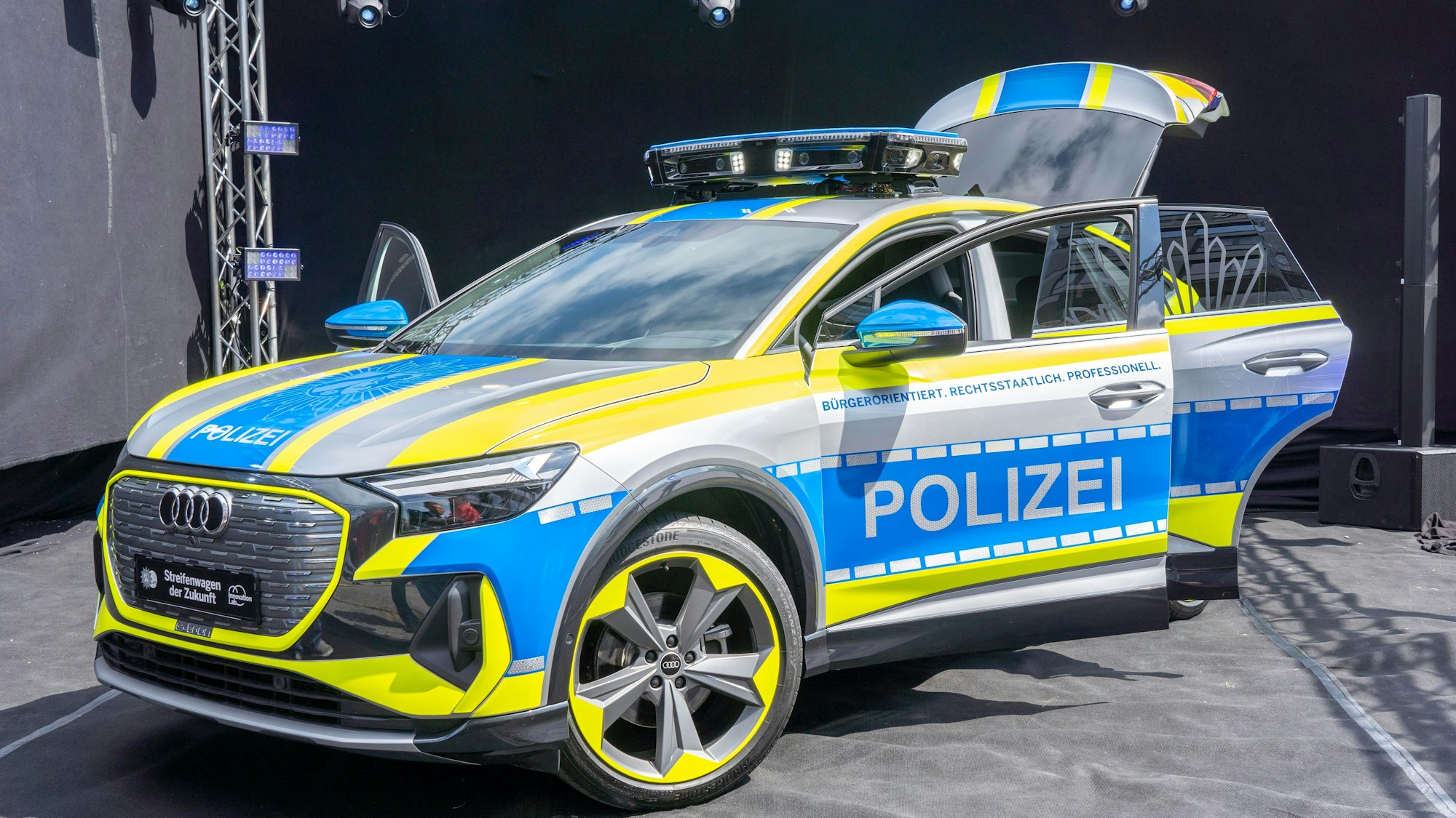 Ein Auto von Audi ist zu sehen mit besonders grelle, gelben Neonstreifen ringsum. Auf blauem Grund ist der Schriftzug Polizei zu lesen.