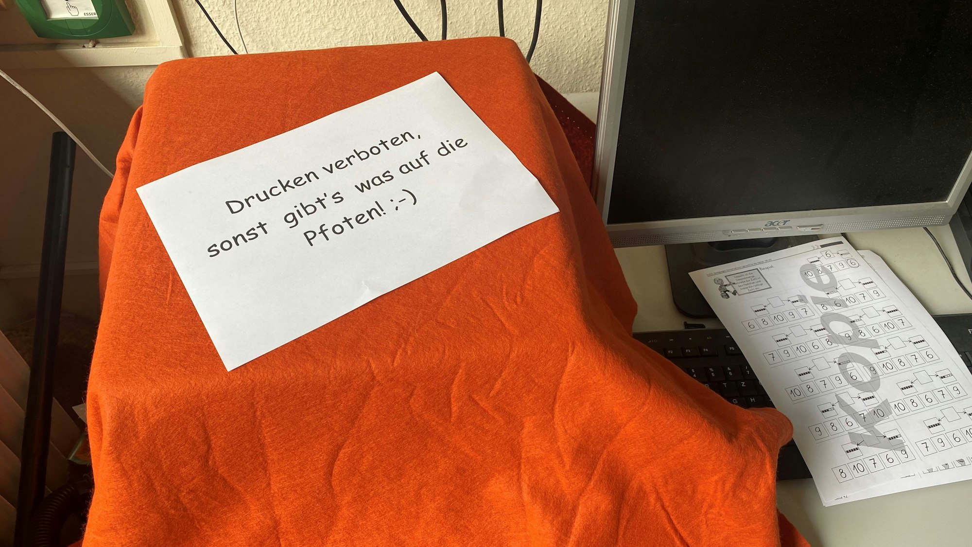 „Drucken verboten, sonst gibt’s was auf die Pfoten“, steht auf einem Schild, das auf dem Drucker liegt.