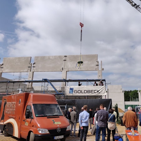 Der Richtkranz baumelt am Kran beim Richtfest für die neue Sporthalle in der Balker Aue. Die Dachbalken fehlen noch.