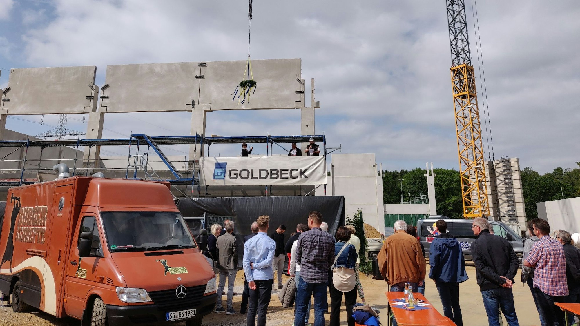 Der Richtkranz baumelt am Kran beim Richtfest für die neue Sporthalle in der Balker Aue. Die Dachbalken fehlen noch.