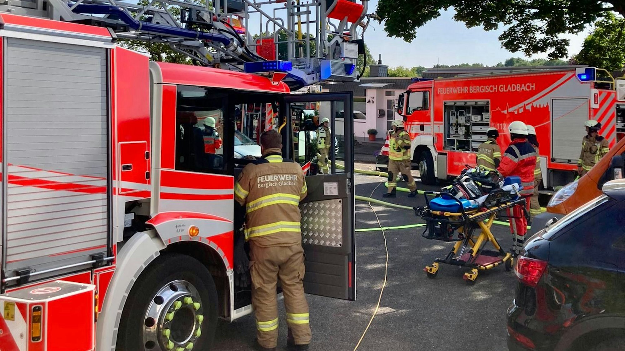 Feuerwehrfahrzeuge stehen auf der Straße, Schlauchleitungen sind ausgerollt, Tragen und Rettungsdienstmitarbeiter stehen bereit.