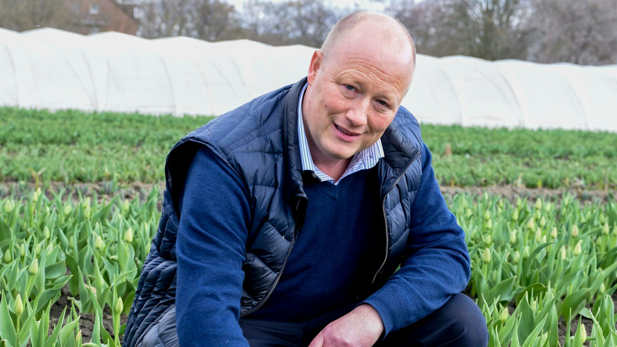 Peter Zens kniet in einem Blumenfeld.
