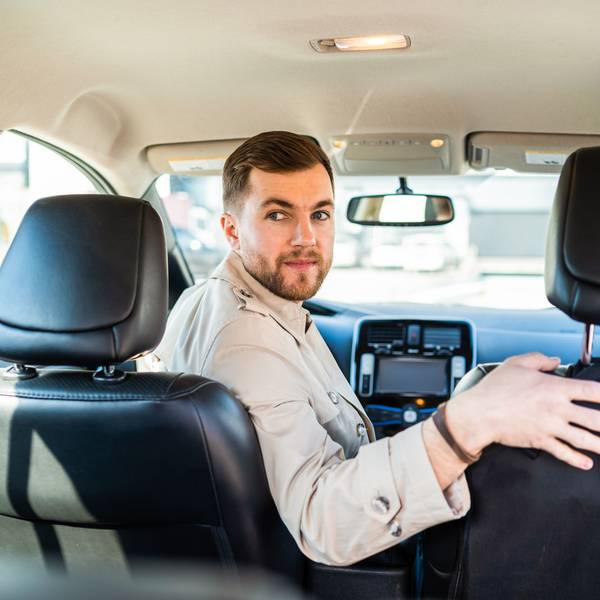 Ein Mann dreht sich auf dem Fahrersitz eines Autos um, um rückwärts einzuparken.