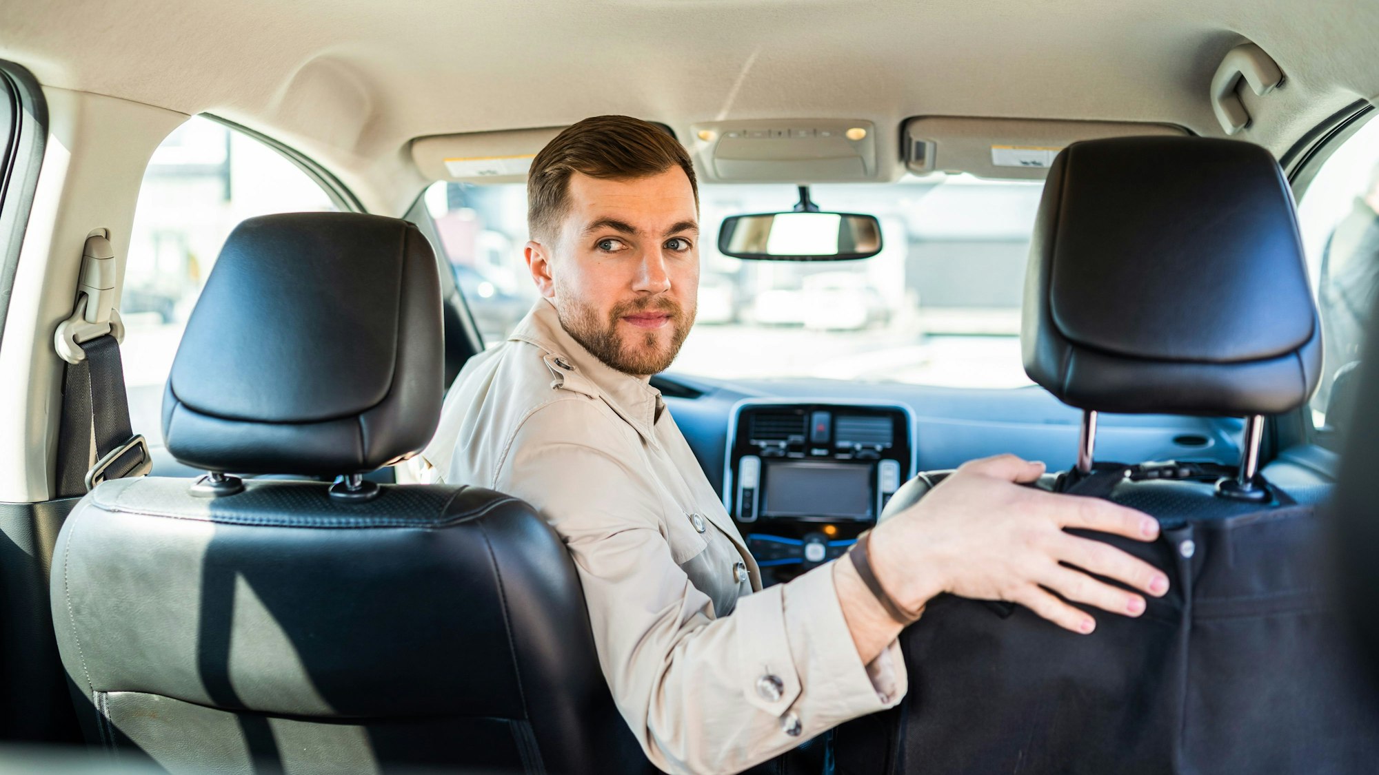 Ein Mann dreht sich auf dem Fahrersitz eines Autos um, um rückwärts einzuparken.