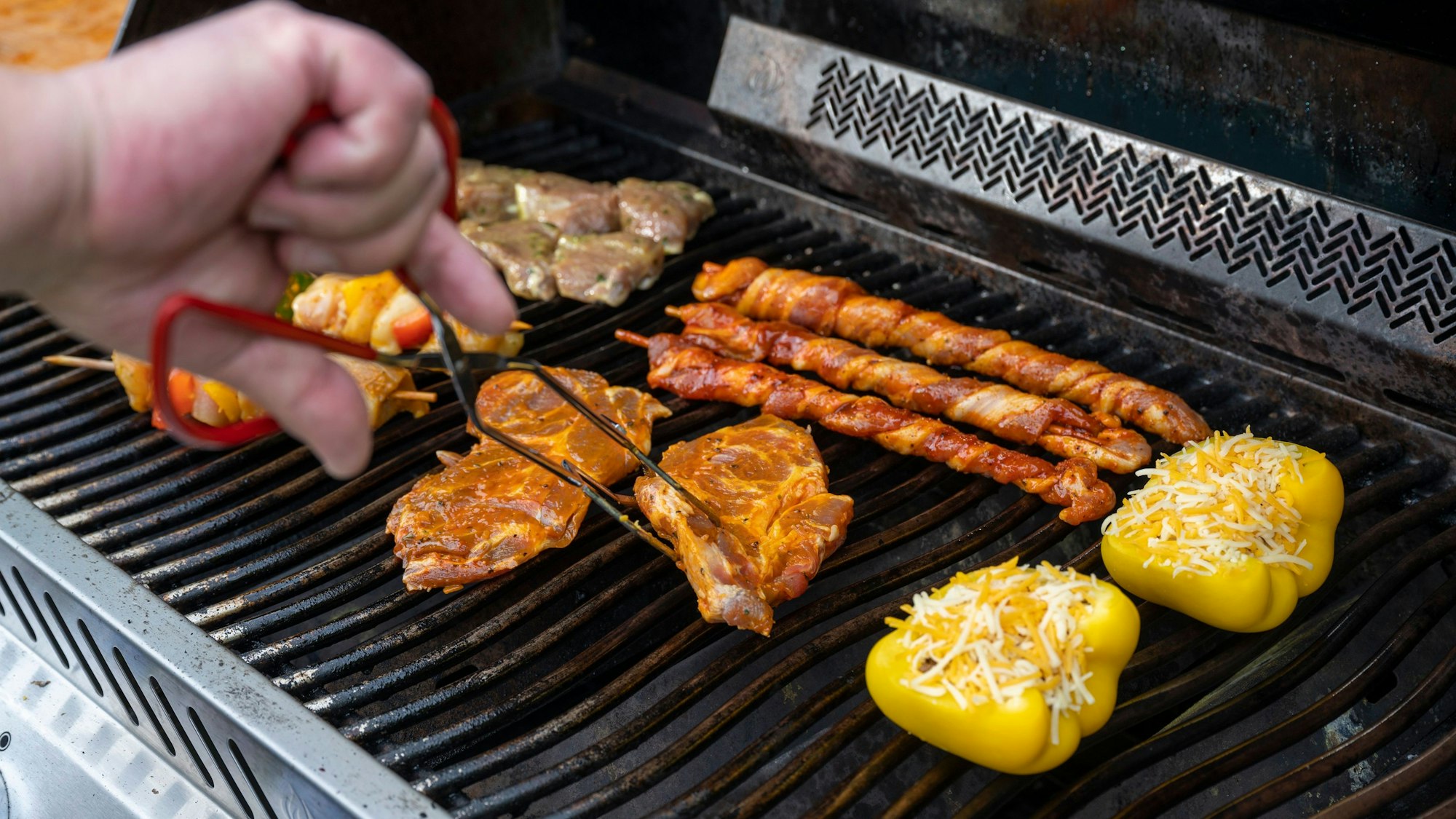 Michael Hoffmann wendet ein Stück Fleisch auf dem Grill mit einer Grillzange.
