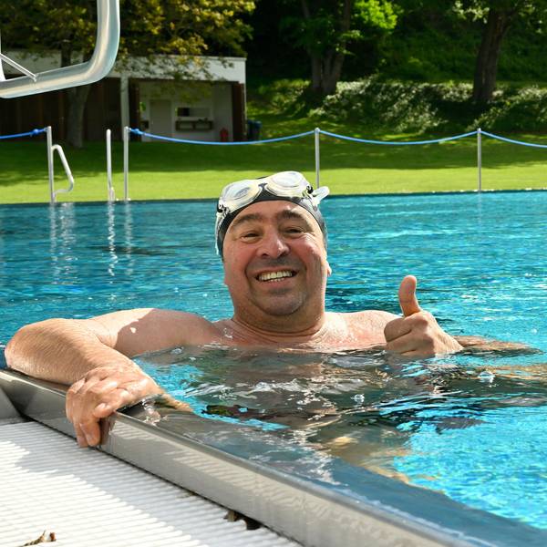 Ein Mann hält sich am Beckenrand des Schwimmeckens fest.