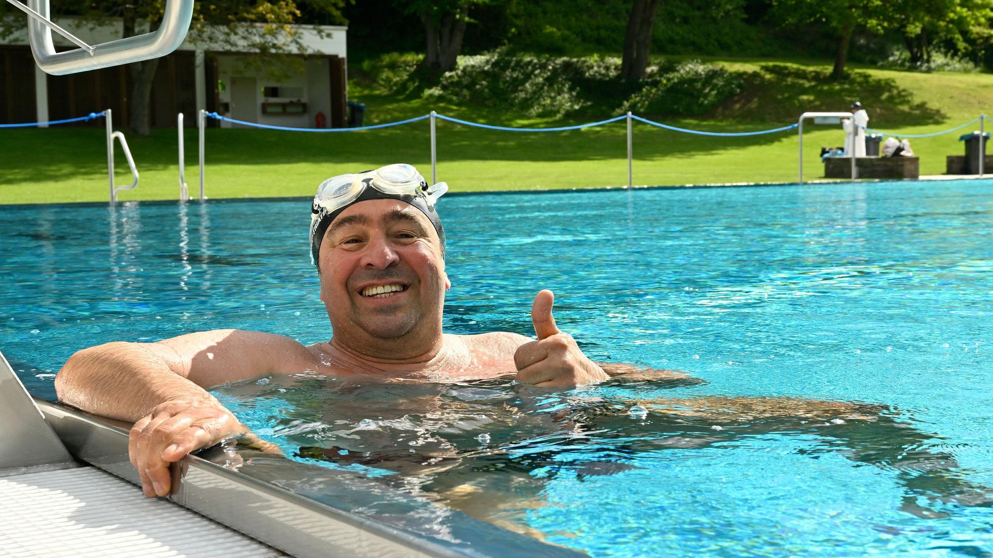Ein Mann hält sich am Beckenrand des Schwimmeckens fest.