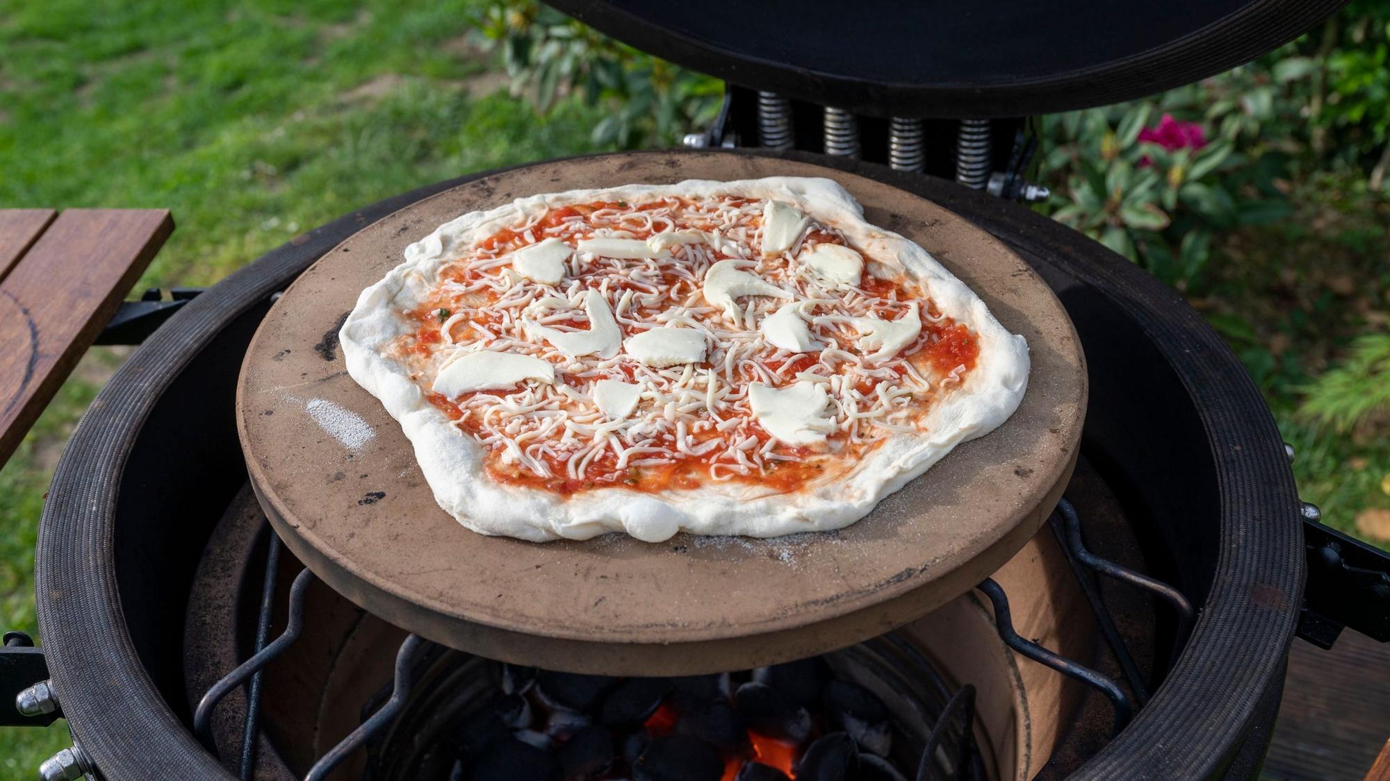 Eine Pizza liegt auf einem Grill.