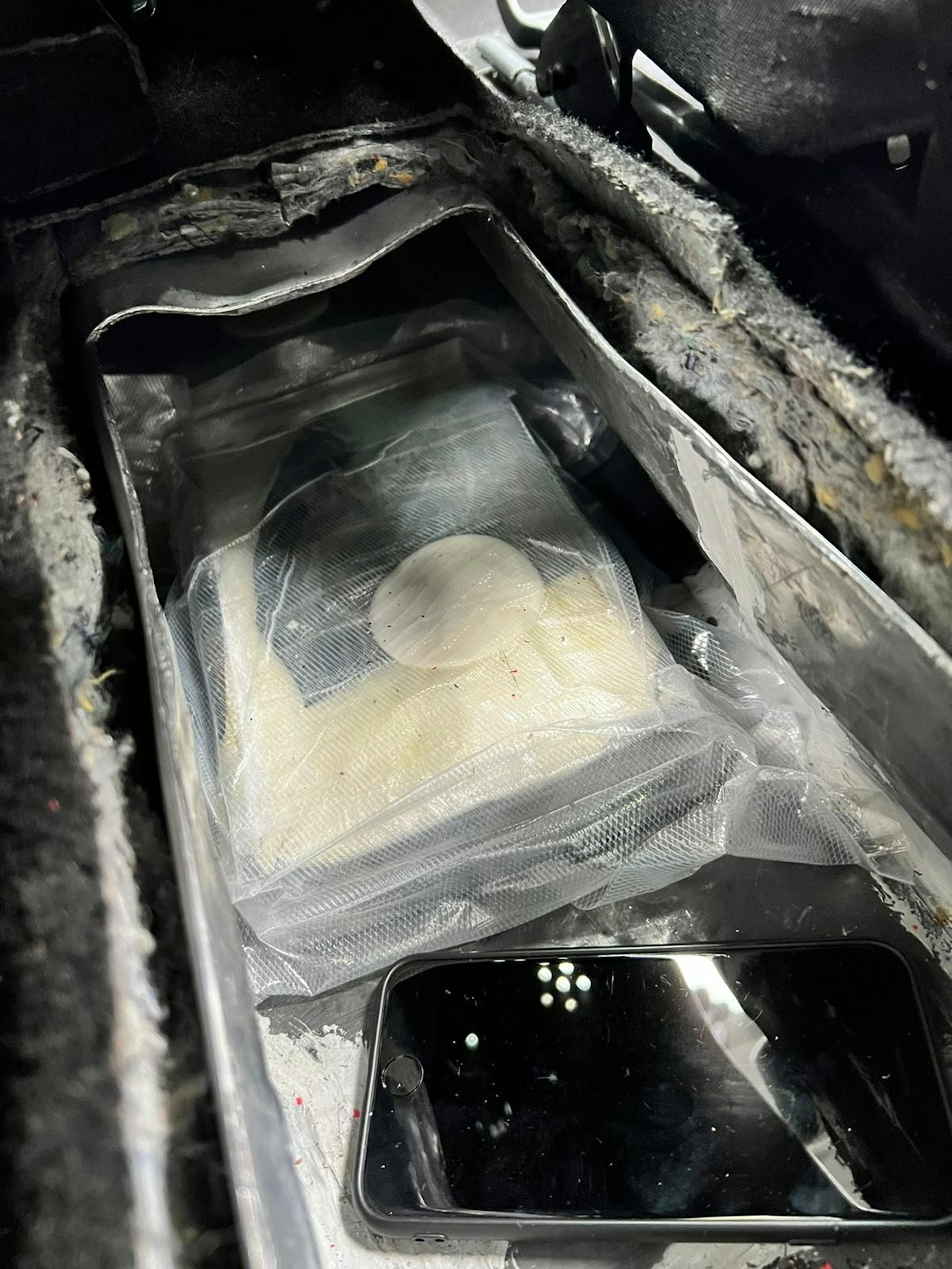 Vier Kokainziegel und ein Smartphone liegen in einem Drogenversteck.