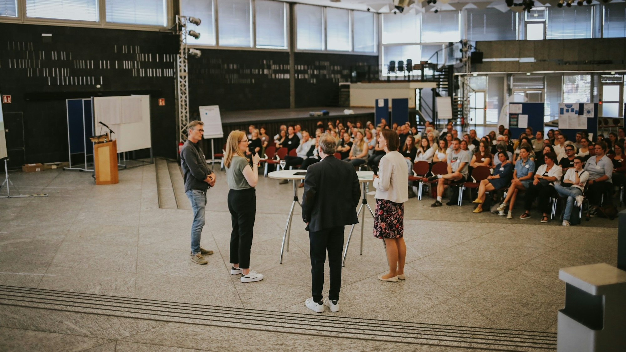 Vier Menschen sprechen vor sitzenden Zuhörern.