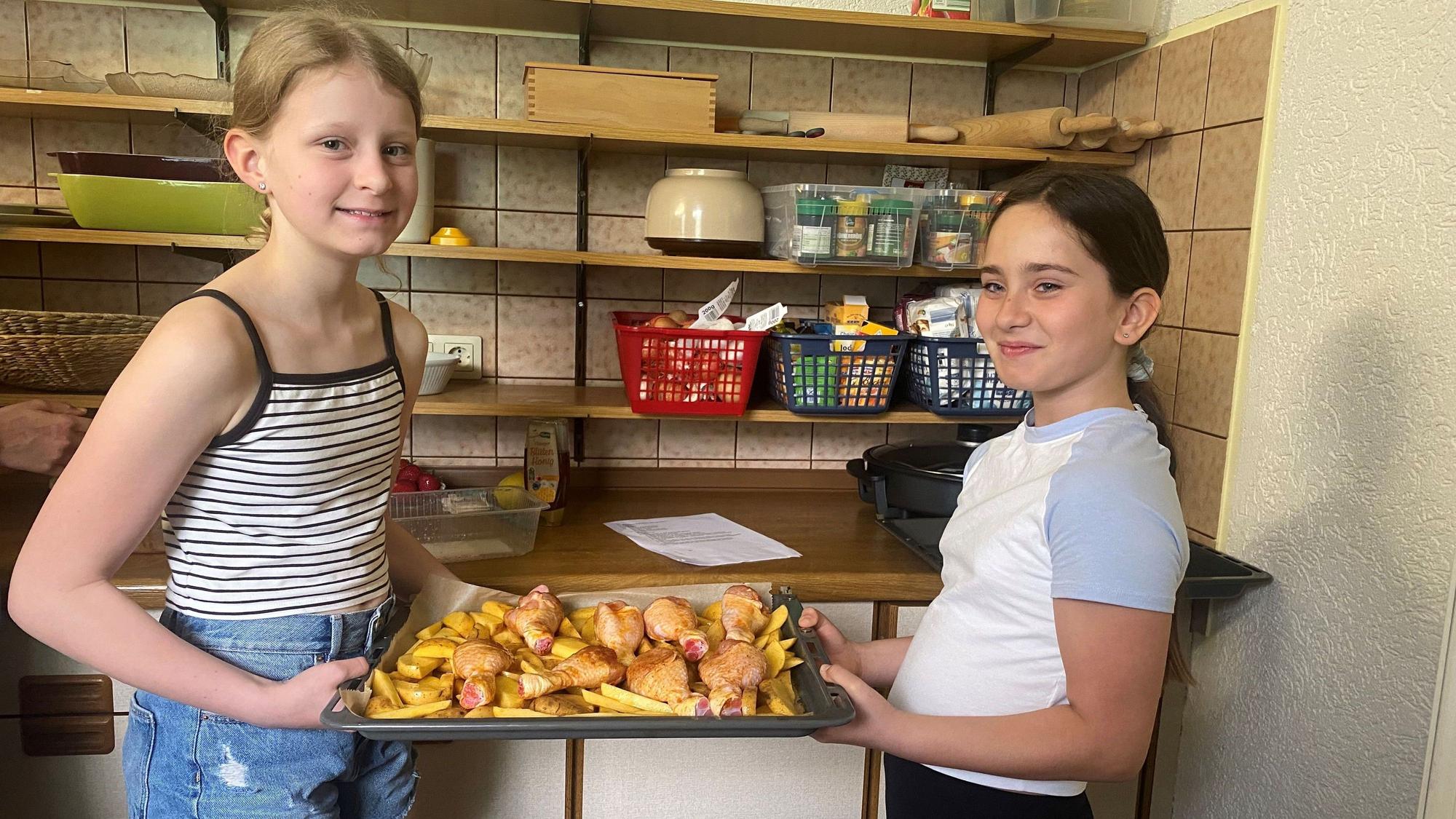 Isabella und Leah mit einem Blech Kartoffeln und Hähnchen